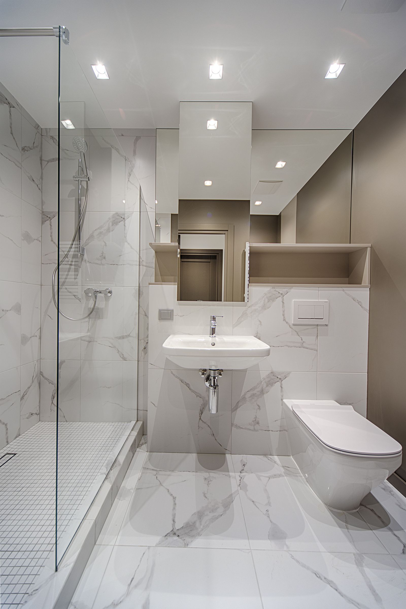 Leeres, sauberes Bad mit Glasdusche, Wand-Lavabo und Wand-WC